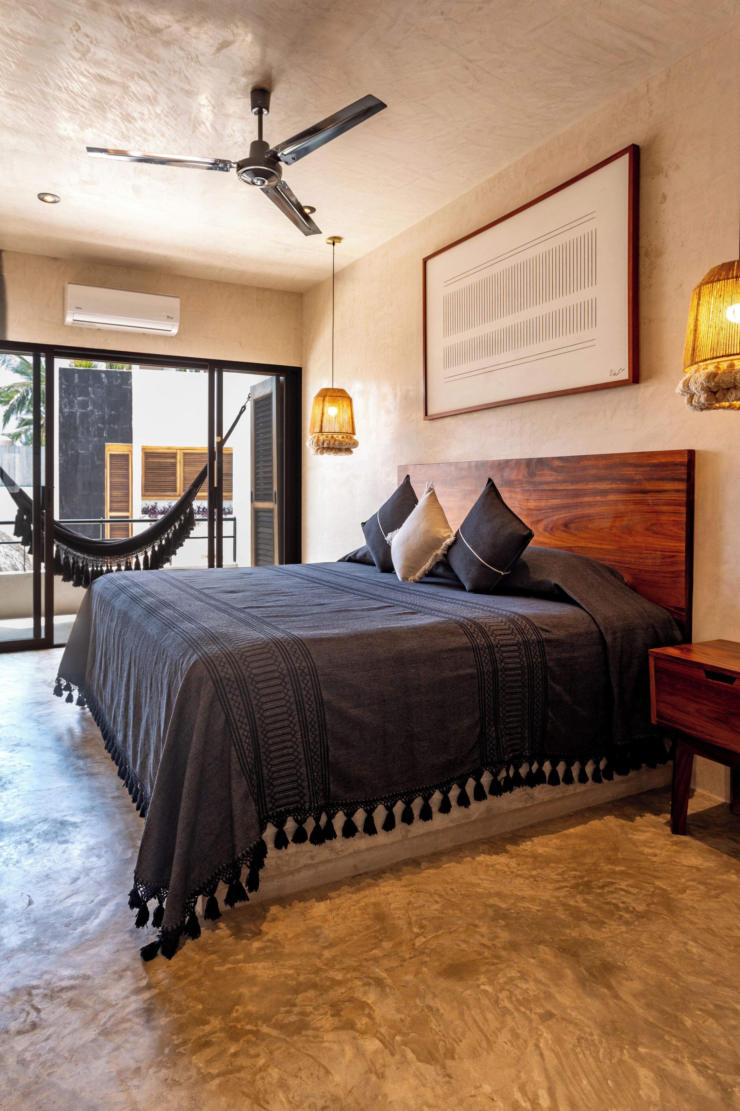 A bedroom with a bed, a hammock, a ceiling fan, and a framed picture on the wall.