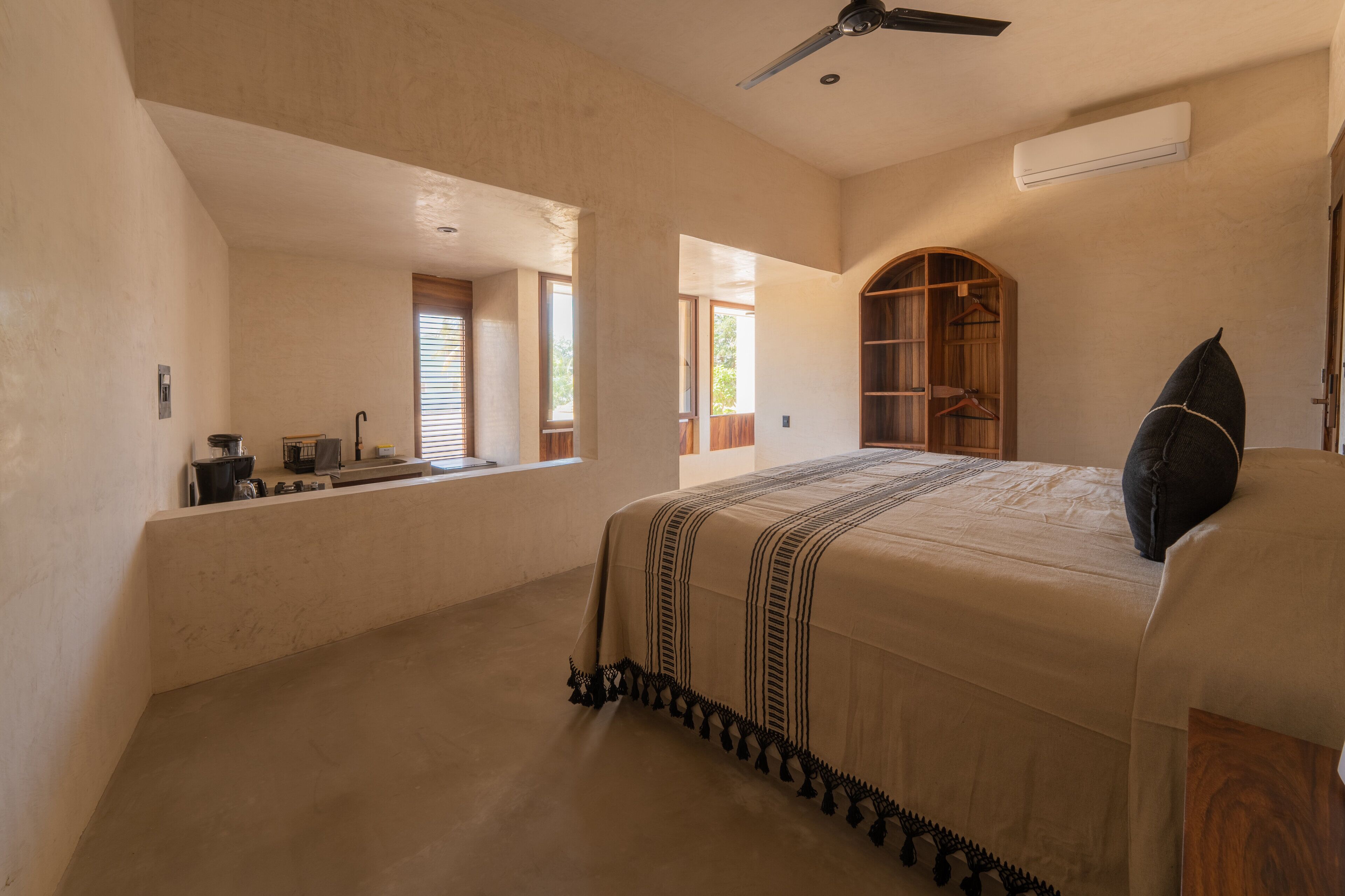 Een slaapkamer met een groot bed, een plafondventilator, een inbouwkast en een raam dat voor natuurlijk licht zorgt.