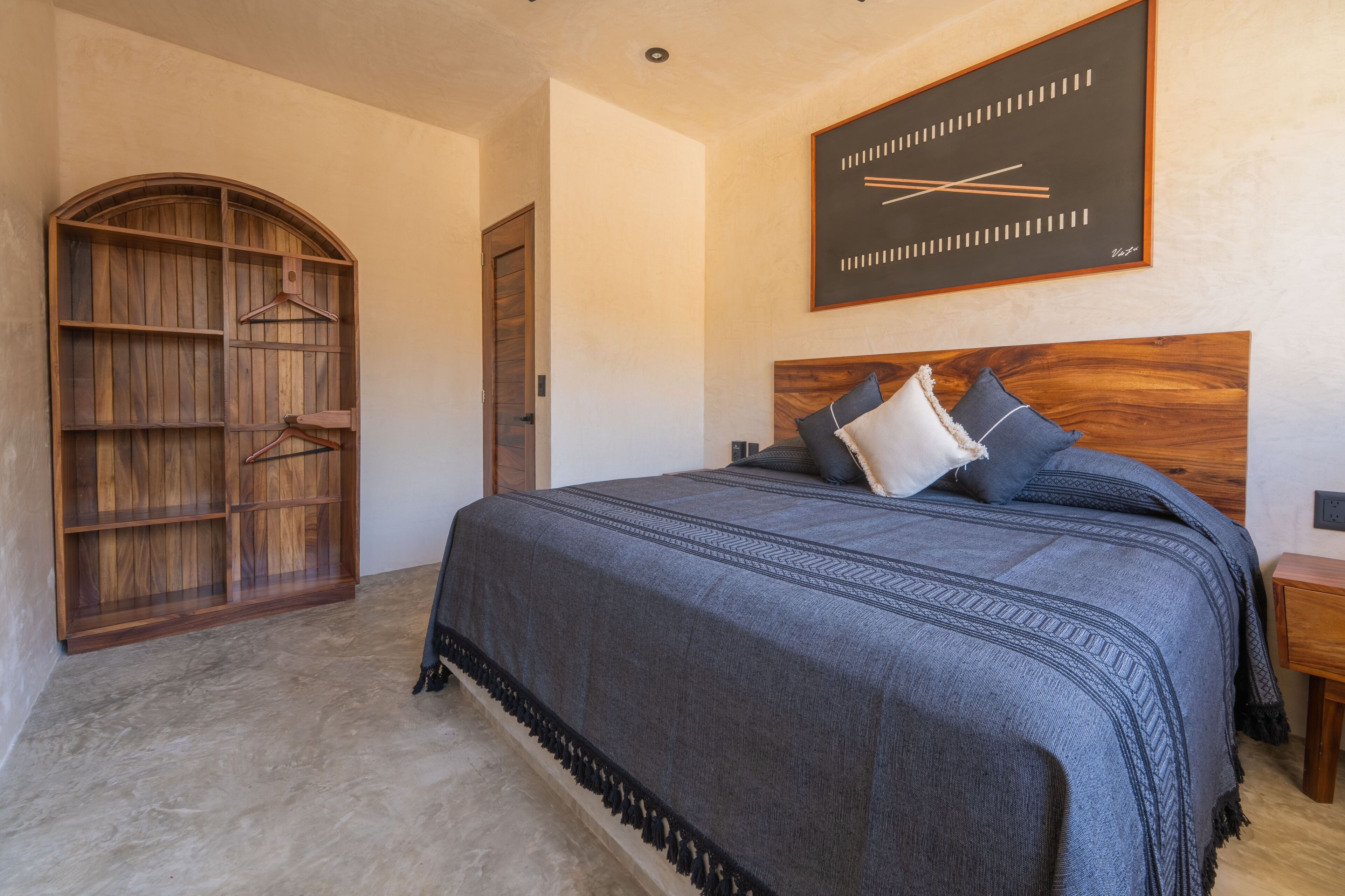 A bedroom with a large bed, a wooden wardrobe, and a wall clock.