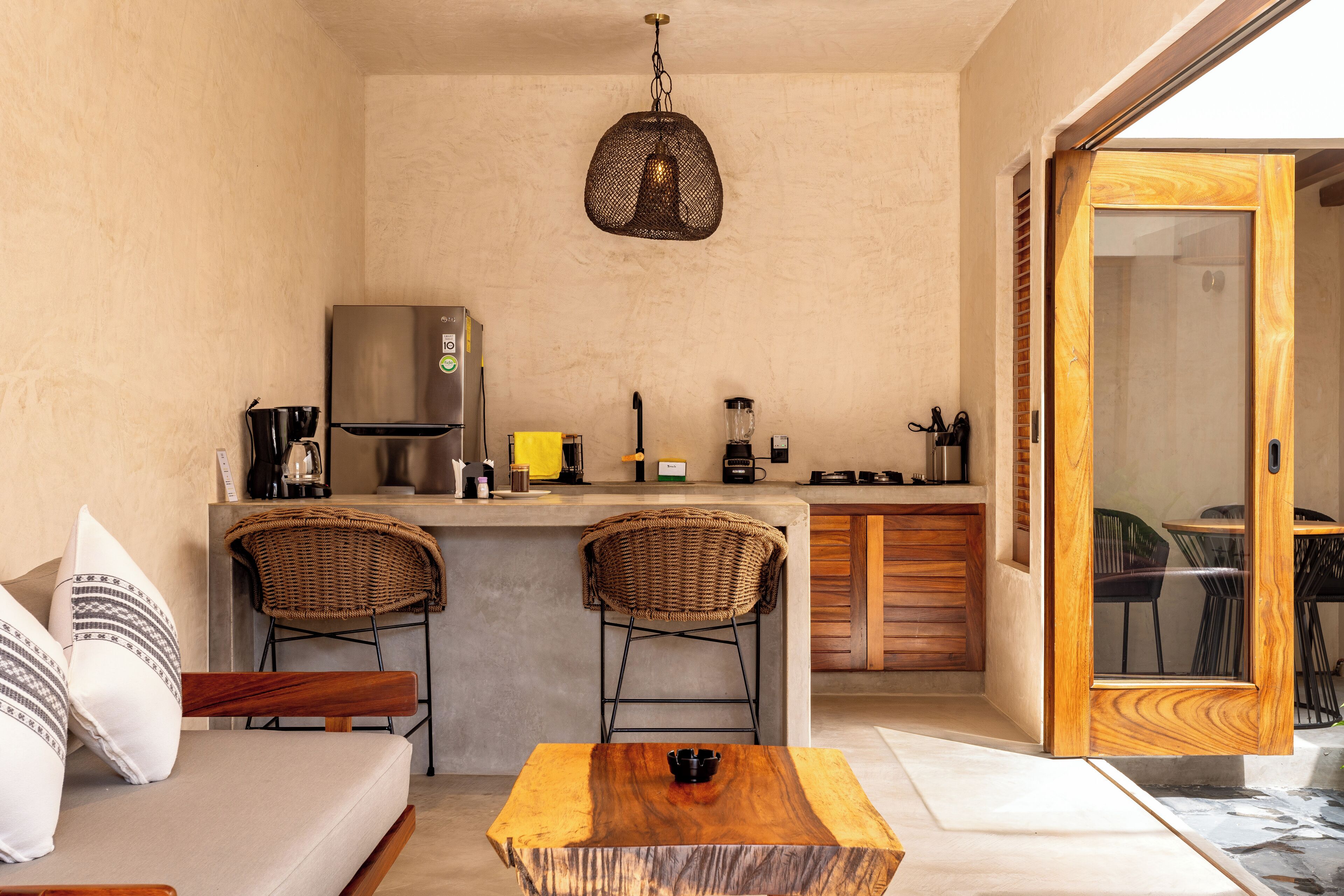 A compact kitchen with a refrigerator, coffee maker, and bar stools.