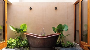Una bañera independiente en un baño moderno de diseño minimalista, rodeada de exuberantes plantas verdes.
