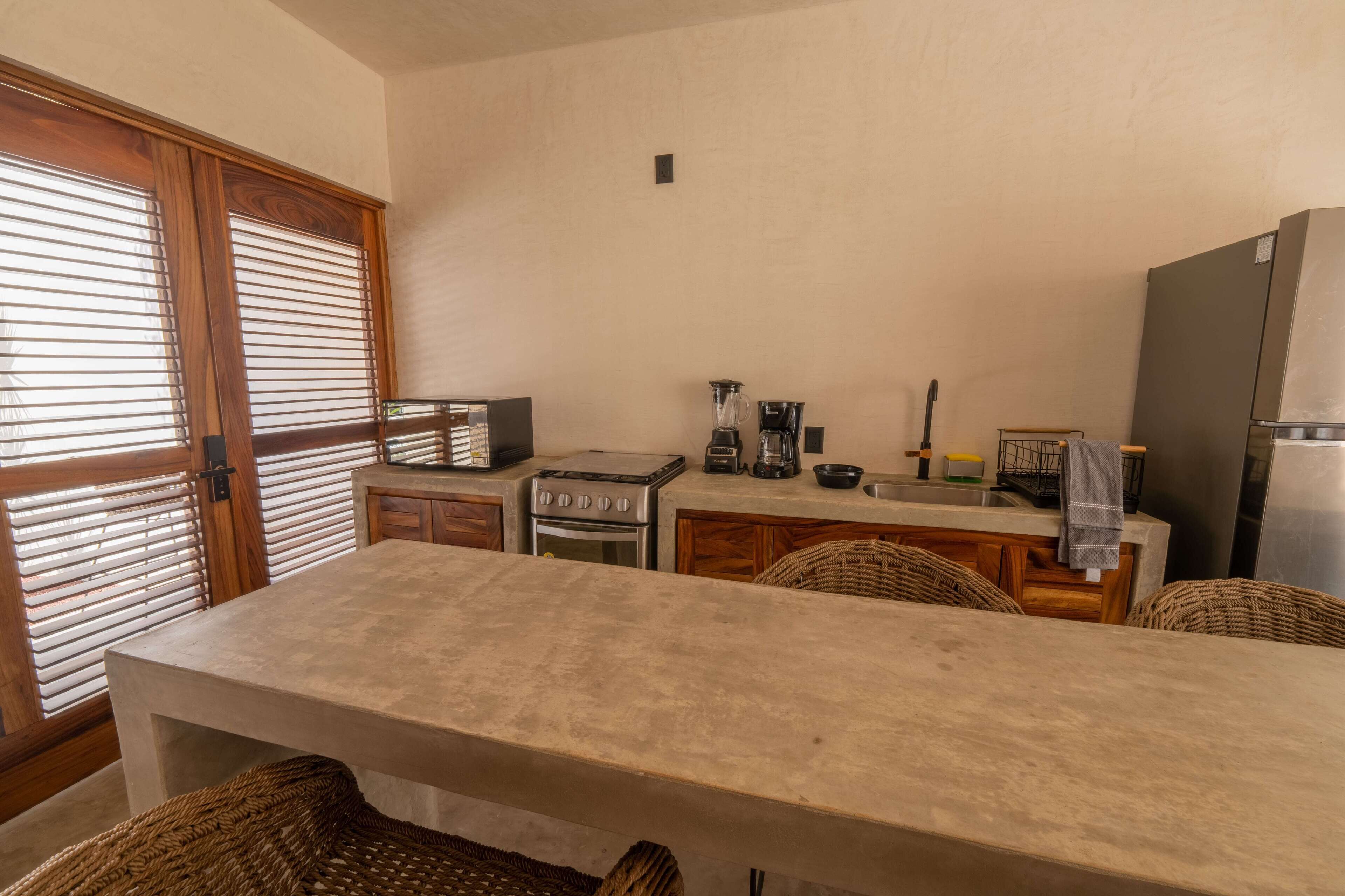 A compact kitchen with a dining area, featuring a stove, oven, and coffee maker.