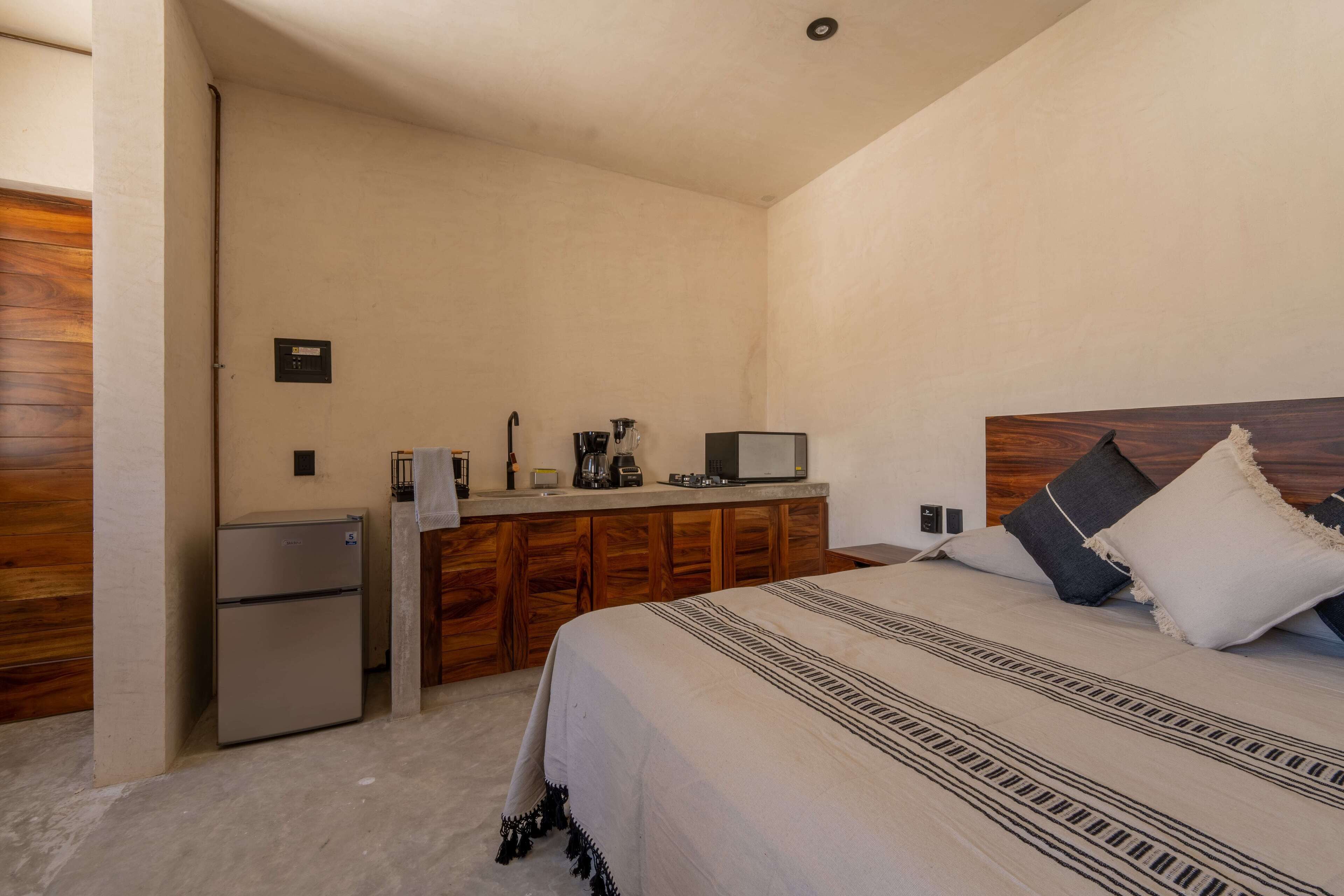 Ein Schlafzimmer mit einem Bett, einer kleinen Küchenzeile und einem Holzkopfende.