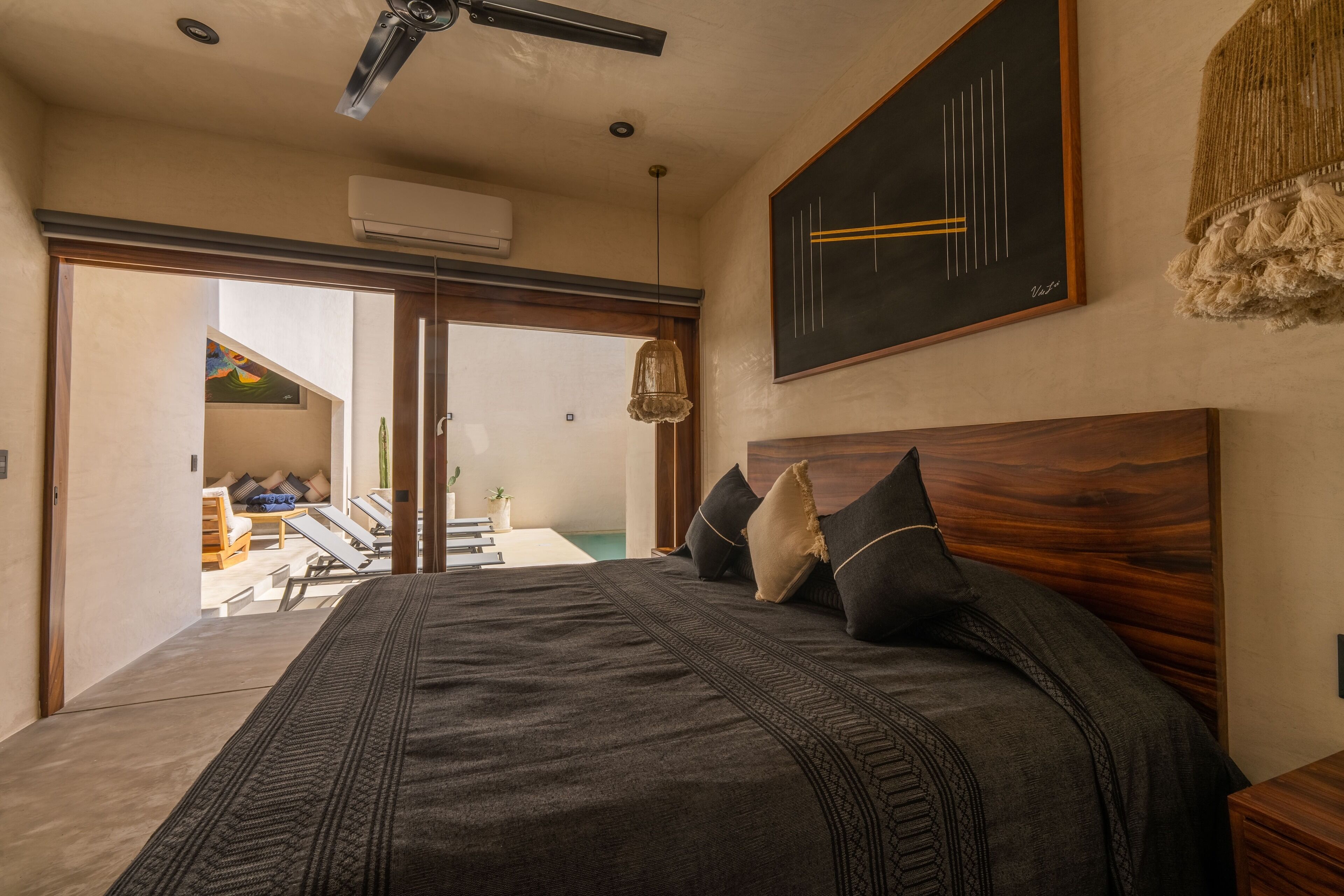 A bedroom with a large bed, wooden headboard, and a view to a balcony.