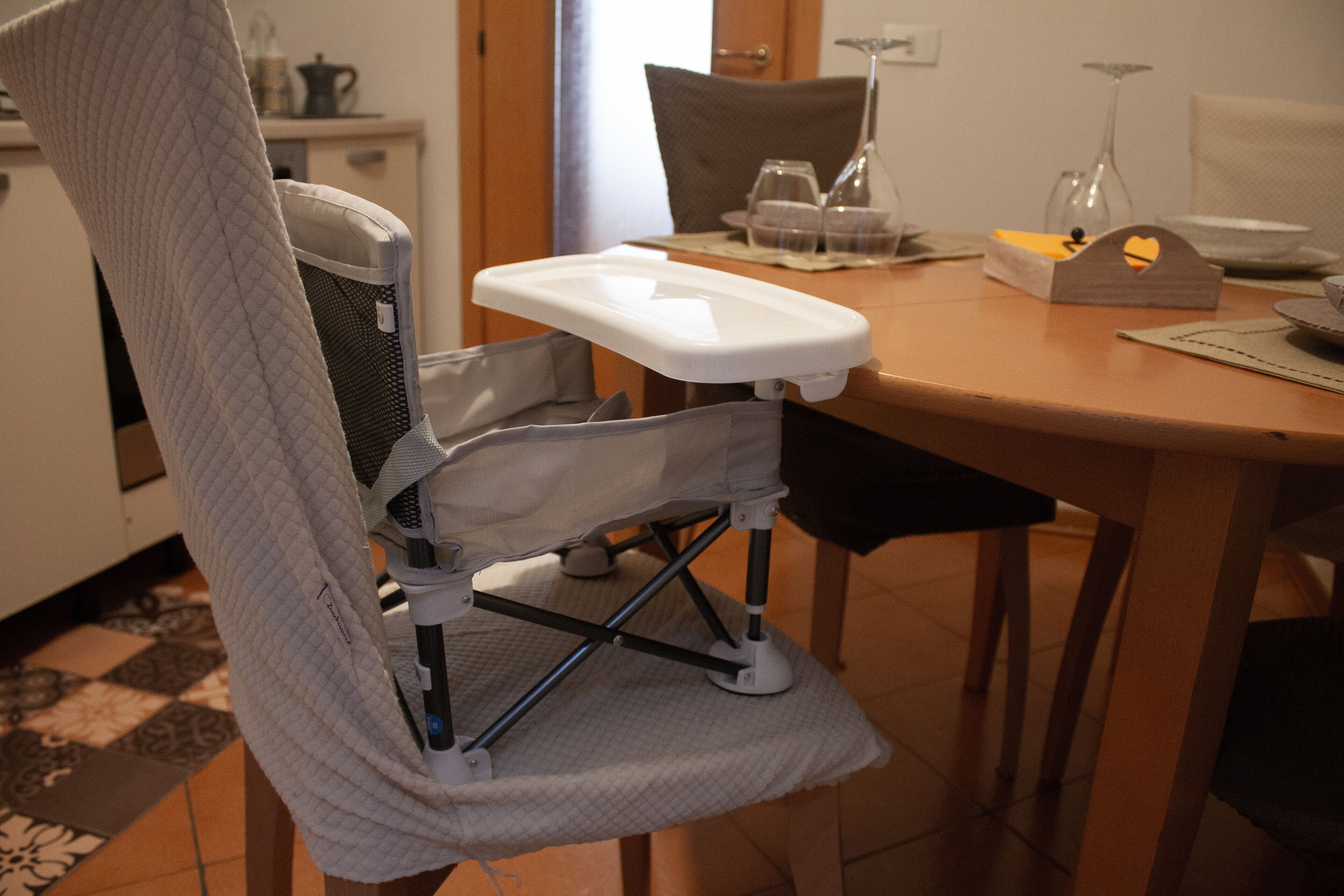 A chair with a tray table, a dining table with a placemat, and a vase on the table.