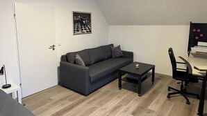 A room with a sofa, a small table, a chair, and a door.