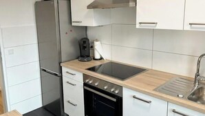 A compact kitchen with a built-in oven, a coffee maker, and a sink.