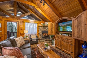 L’intérieur d’une cabane en rondins, avec une cheminée, des meubles en bois et un téléviseur.