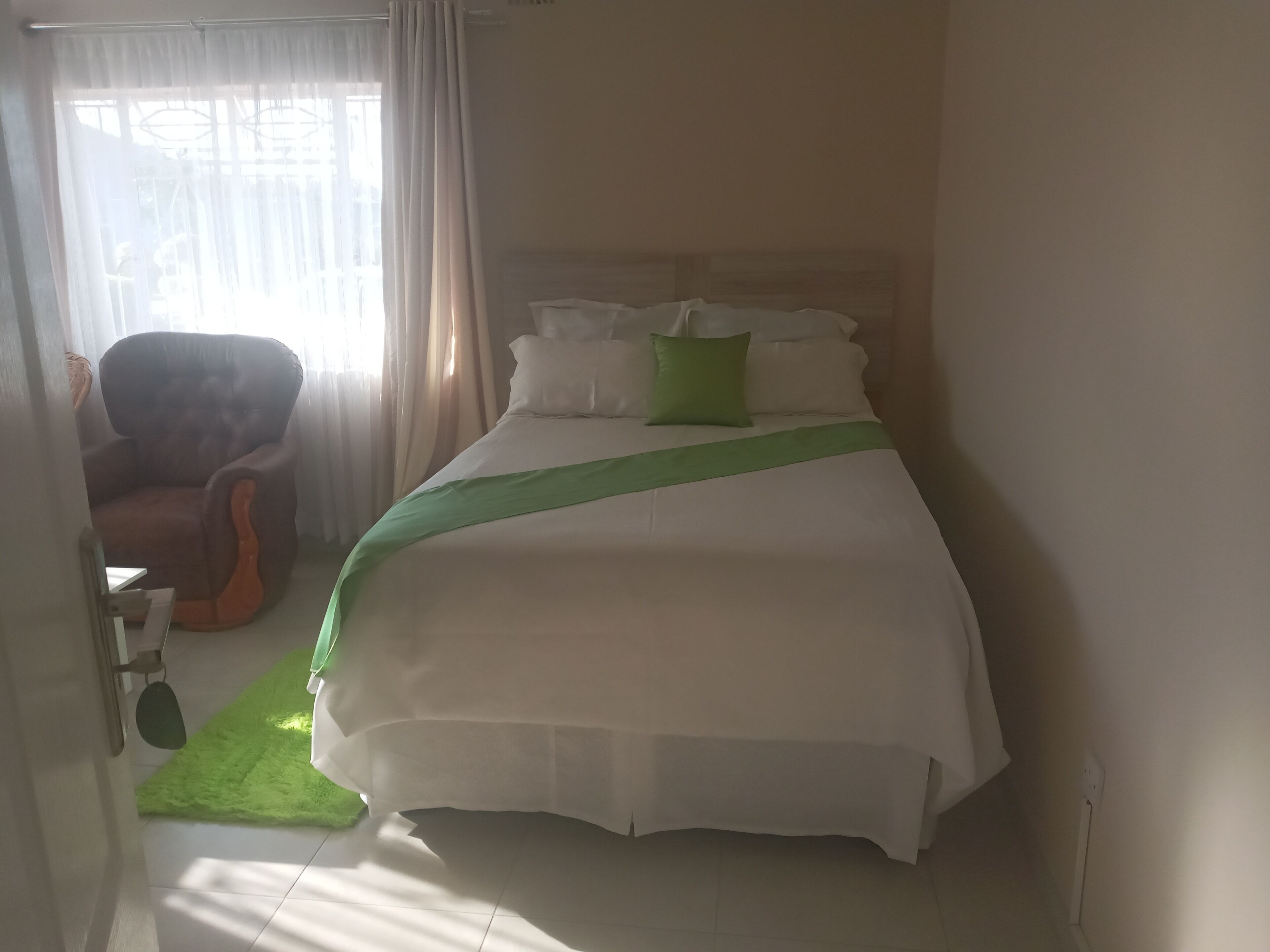 Habitación de hotel con cama, una silla y ventana con cortinas.