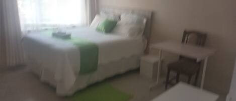 Quarto com uma cama, uma escrivaninha e uma cadeira.