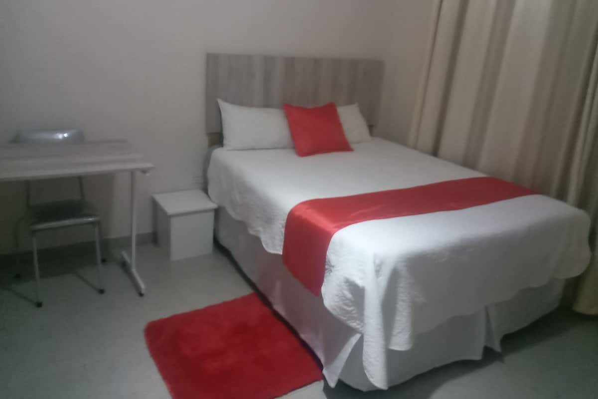 A hotel room with a bed, a desk, and a chair.