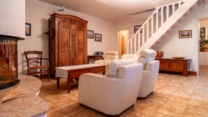 A living room with a fireplace, a wooden cabinet, a sofa, and a staircase.