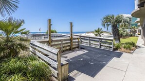 Une promenade en bois menant à une plage bordée de palmiers, sous un ciel bleu et dégagé.