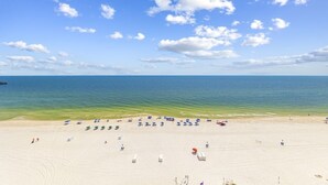 Une plage avec un ciel dégagé, une eau calme et des parasols.