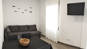 Uma sala de estar moderna com sofá, mesa de jantar com cadeiras, televisão de tela plana na parede e arte decorativa de peixes.