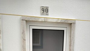 Uma porta com uma placa de identificação com o número 90 acima, um cadeado eletrônico e uma porta de vidro com moldura de metal.
