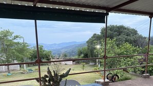 An outdoor patio with a checkered tablecloth, white chairs, and a potted plant. - Sítio Aconchegante em Amparo/sp com uma Linda Vista Para Apreciar o pôr do sol (AMPARO)