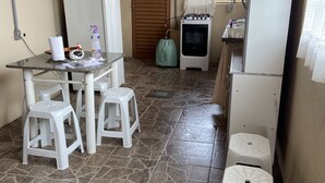A compact kitchen with a dining area, including a table with stools, a refrigerator, a gas stove, and a sink. - Sítio Aconchegante em Amparo/sp com uma Linda Vista Para Apreciar o pôr do sol (AMPARO)