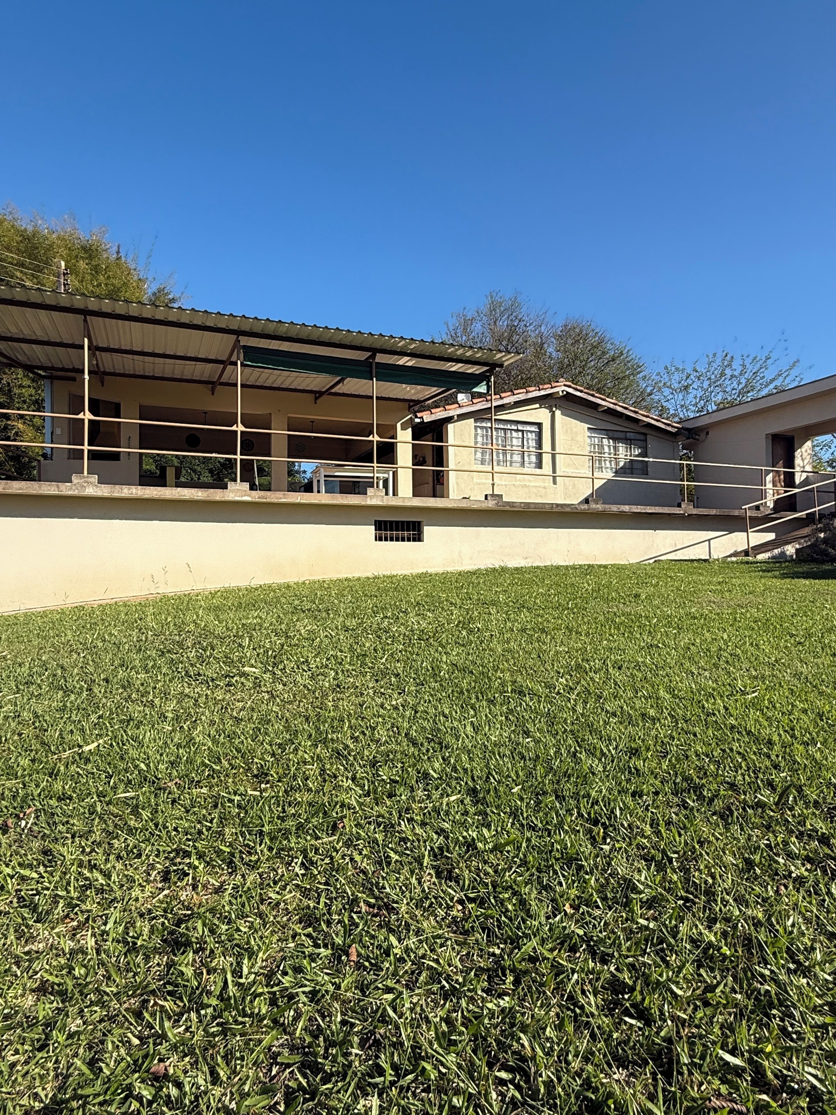 A building with a covered outdoor area and a grassy field in front.