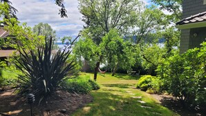 Un jardín con un camino de piedra, una hamaca y diversas plantas.