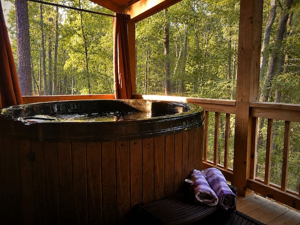 Un jacuzzi en una cabaña de madera con vistas a un bosque.