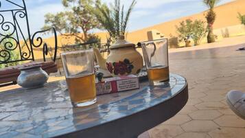 A table with two glasses of amber liquid, a teapot, and a box of tea.
