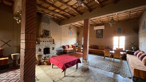 Una habitación rústica con chimenea de ladrillo, una mesa roja y una alfombra estampada.