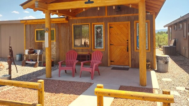 A wooden cabin with a covered patio, two red chairs, and a wooden table. - Miners Cabin - New Private and Cozy (Cottonwood)