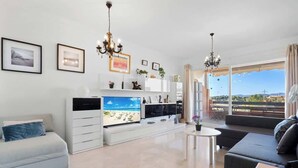A modern living room with a flat-screen TV, a sofa, a coffee table, and a balcony with a view. - Torreblanca with pool by Costarentals - Ref 63 (Fuengirola)