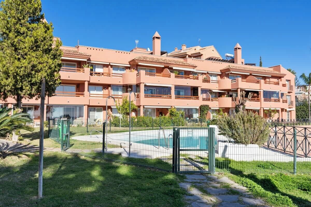 Un hotel su più piani con balconi, una piscina e un cortile recintato.