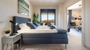 A modern bedroom with a bed, bedside table, and a large window. - La Cala de Mijas Modern Flat with Pool - ref 240 (Las Lagunas de Mijas)
