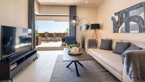 A modern living room with a flat-screen TV, a sofa, a coffee table with candles, and a large abstract painting on the wall. - La Cala de Mijas Modern Flat with Pool - ref 240 (Las Lagunas de Mijas)