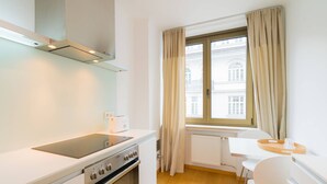 Eine moderne Küche mit Backofen, Kochfeld und einer kleinen Essecke mit Tisch und Stühlen.
