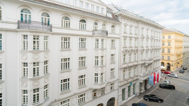 Ein mehrstöckiges Hotel mit weißen Fassaden, großen Fenstern und Balkonen.