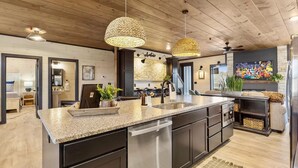 Una cocina moderna con una isla grande, electrodomésticos de acero inoxidable y techo de madera.