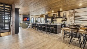 Una cocina moderna con una isla central, asientos tipo bar y un televisor.