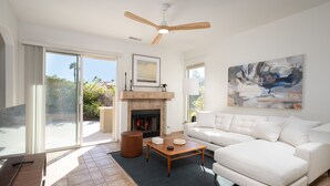 A modern living room with a fireplace, a white sofa, a coffee table, and a ceiling fan. - The Desert Flower, designer home in gated community/ private pool and jacuzzi. (Palm Springs)