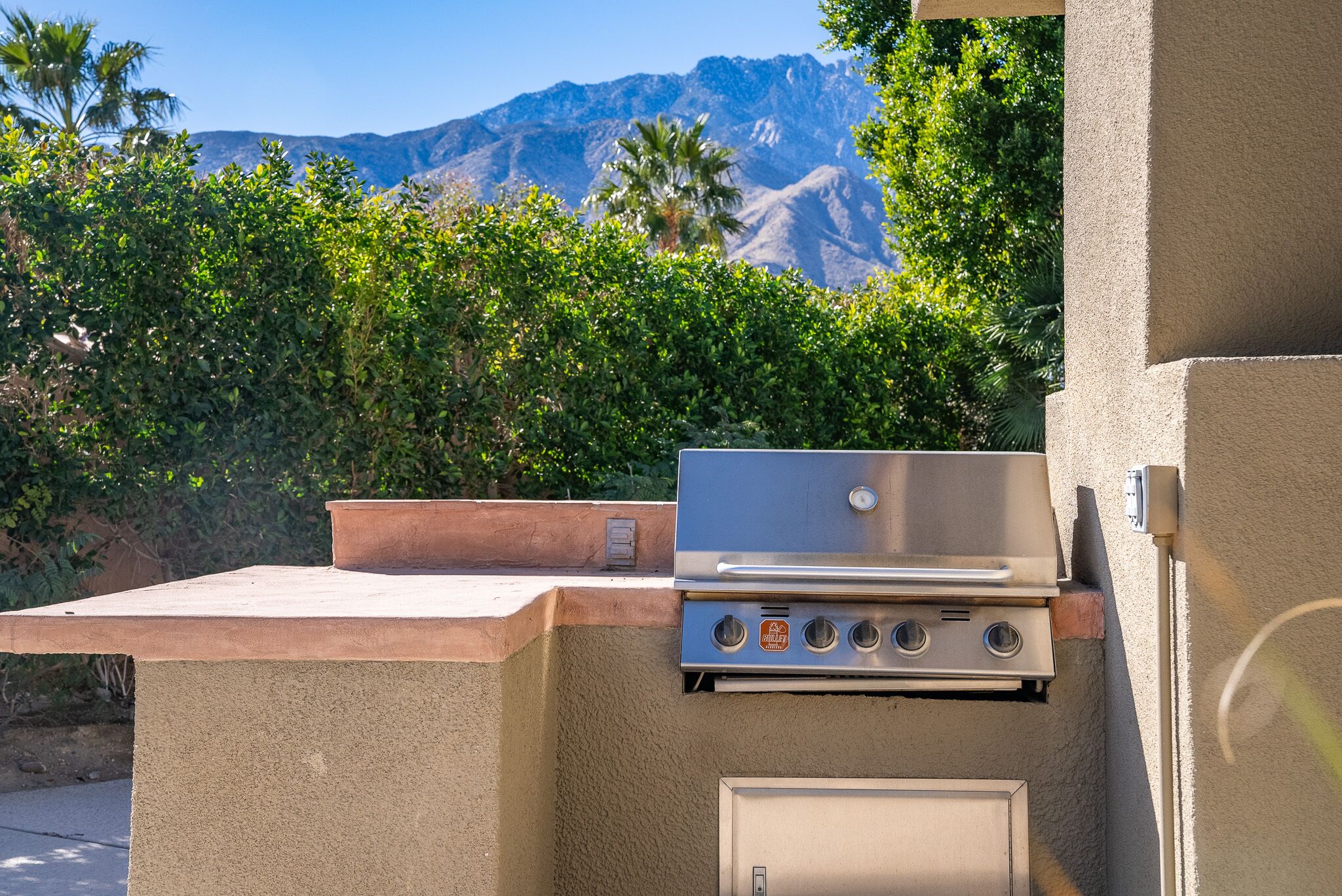 Un barbecue extérieur offrant une vue sur les montagnes et la verdure.