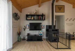 Un salon avec un téléviseur, des étagères noires, une cheminée et une pancarte indiquant « BIENVENUE ».