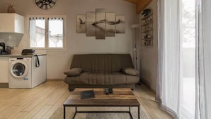 A living room with a sofa, a coffee table, a washing machine, and a wall clock.