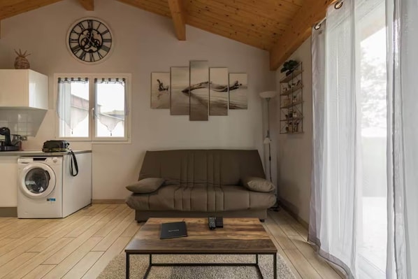 A living room with a sofa, a coffee table, a washing machine, and a wall clock.