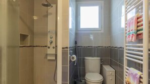 Un baño con ducha, inodoro y ventana.