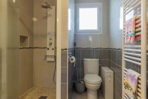 Ein Badezimmer mit Dusche, Toilette und einem Fenster.