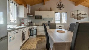A kitchen with white cabinets, a microwave, an oven, a sink, and a dining table with chairs.