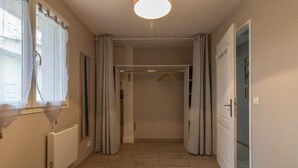 A bedroom with a bed, a radiator, a window with curtains, and a door leading to a bathroom.