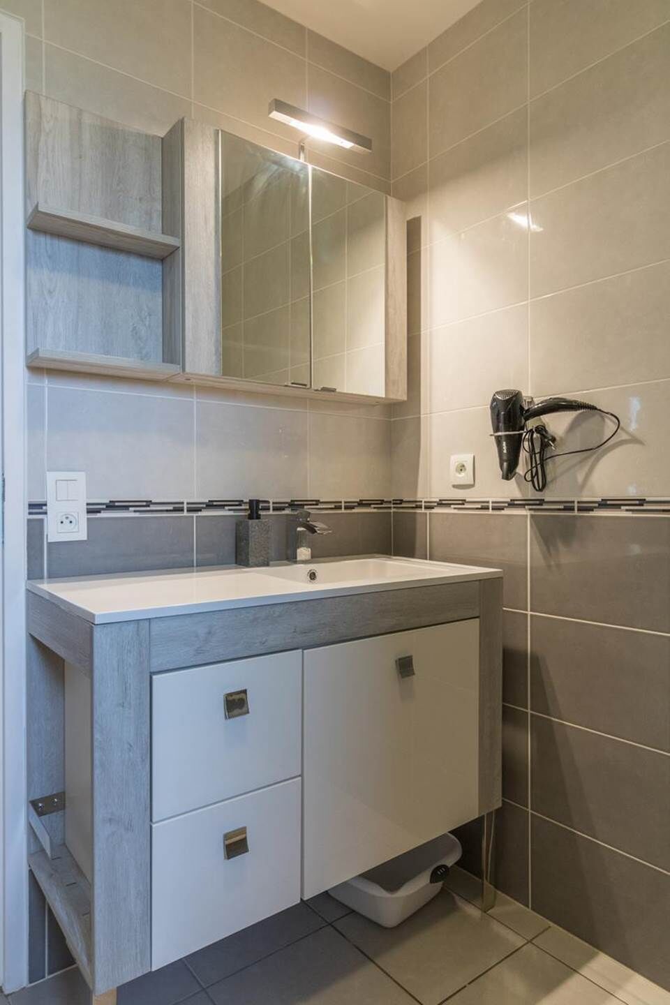 A bathroom with a sink, mirror, and hairdryer.
