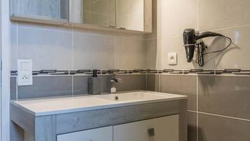 A bathroom with a sink, mirror, and hairdryer.