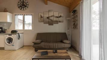 A living room with a sofa, a coffee table, a washing machine, and a wall clock.