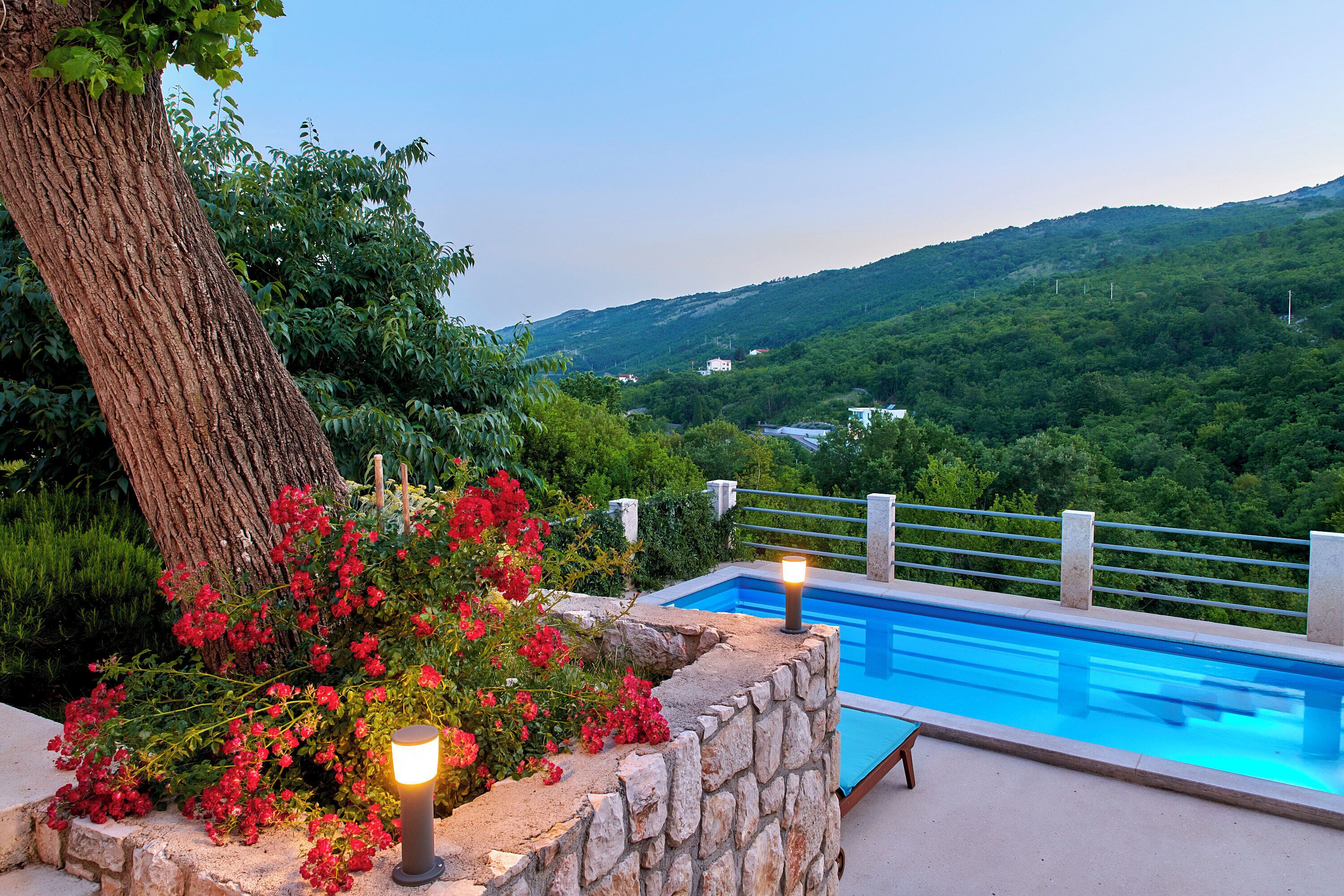Piscina com paredes de pedra e vista para uma paisagem verde.
