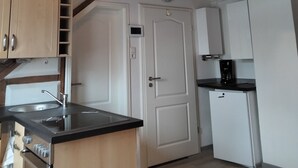 A compact kitchen with wooden beams, white cabinets, a built-in oven, and a coffee maker.